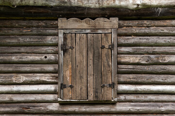 A vintage wooden window with closed shutter set against the textured exterior