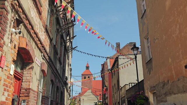 Cinematic old town in Grudziadz with flags hanging above narrow street view