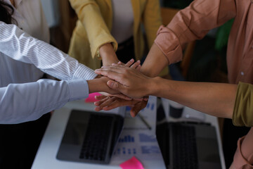Group of asian workers in the office put their arms together and celebrate success. Success in business, startup, joy at work
