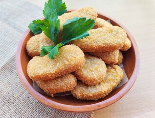 Fried chicken nuggets in a wooden plate on the table.