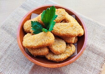 Fried chicken nuggets in a wooden plate on the table.