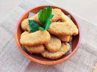 Fried chicken nuggets in a wooden plate on the table.