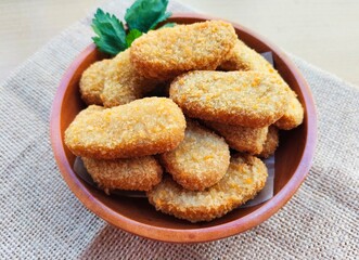Fried chicken nuggets in a wooden plate on the table.