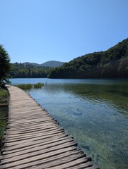 Serene boardwalk over clear water in Plitvice Lakes.