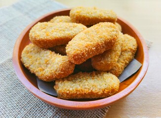 Fried chicken nuggets in a wooden plate on the table.