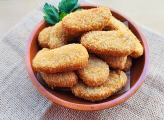 Fried chicken nuggets in a wooden plate on the table.