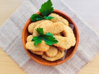 Fried chicken nuggets in a wooden plate on the table.