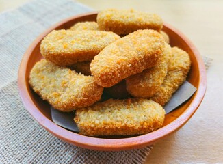 Fried chicken nuggets in a wooden plate on the table.