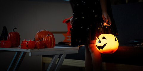 Halloween. Child with pumpkin lantern and festive decorations in cozy setting.