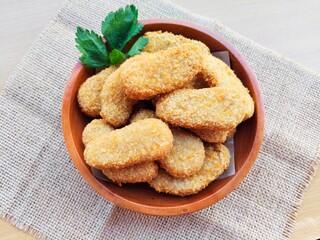 Fried chicken nuggets in a wooden plate on the table.