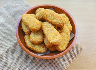 Fried chicken nuggets in a wooden plate on the table.
