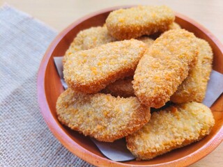 Fried chicken nuggets in a wooden plate on the table.