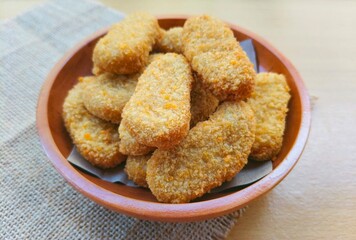 Fried chicken nuggets in a wooden plate on the table.