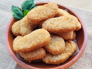 Fried chicken nuggets in a wooden plate on the table.