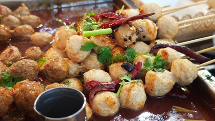 Grilled meat balls and red sausage with spicy sauce.
