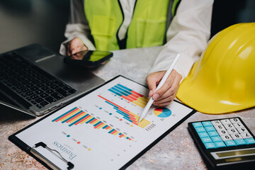 Professional worker analyzes data with graphs and charts using laptop, smartphone, and calculator on desk