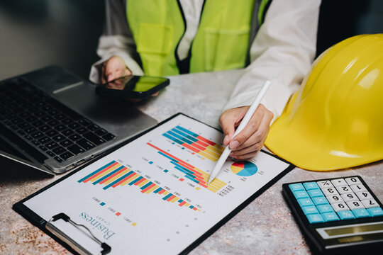 Professional worker analyzes data with graphs and charts using laptop, smartphone, and calculator on desk