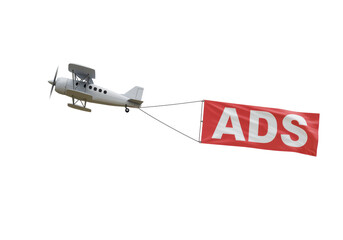 Isolated vintage biplane pulling red banner with word Ads against the sky, aerial advertising