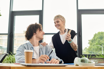 Two youthful individuals engage in a friendly conversation, fostering a positive work environment