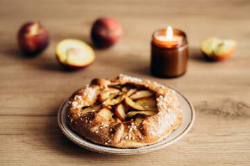 Appetizing homemade peach galette on wooden kitchen table.