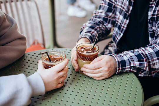 A man and a woman are drinking iced coffee and orange juice on a cafe terrace.