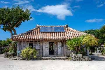 Obraz premium Rustic Okinawan stone house in Japan with orange tiled roof and rooftop solar panels.