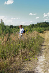A young woman is looking for mushrooms in a young mixed forest.
