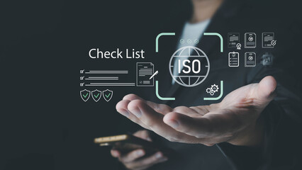 A businessman presents a digital hologram showing the ISO standard certification process, including a checklist and quality control icons, representing business technology and quality assurance.