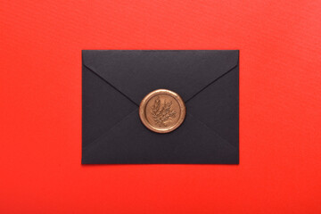 Black envelope with wax seal isolated on red background