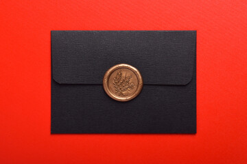 Black envelope with wax seal isolated on red background