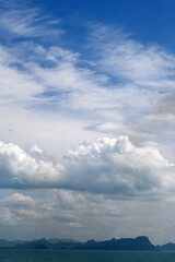 Serene Seascape with Clouds and Mountains Under Expansive Blue Sky