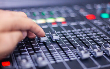 Mixer. Manual volume slider adjustment on a black audio mixer in a dark studio with multiple control knobs and buttons. Concert sound control.