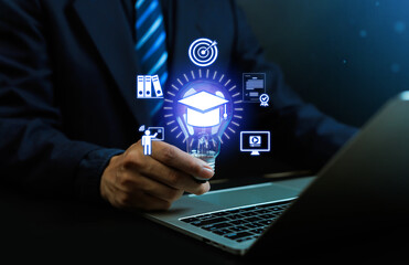 Fototapeta premium Businessman holding light bulb with digital graduation cap icon, concept of online education, e-learning, innovation, training, academic success, modern knowledge, and technology development.
