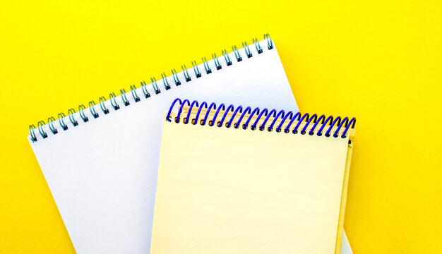 White and beige notepads on a yellow background.