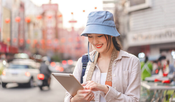 Young adult asian woman traveler backpack travel using digital tablet ai browsing recommend guide good rating restaurant