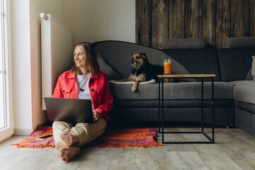 Smiling woman with dog filming on smartphone at home. Remote work, freelance lifestyle, online...