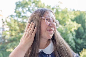 Middle aged woman 50 years old, human ear ringing, listening, acoustics Auditory System, Hearing Test, Cochlear implant, Assistive listening device, healthy aging, quality mature life, health check