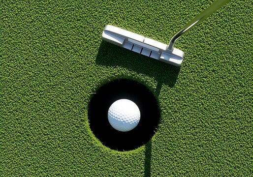 A golf putter rests above a white golf ball positioned in the cup of a putting green.