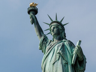 Fototapeta premium Detailed close-up of the Statue of Liberty in New York City, focusing on her face, crown, raised torch, and the book in her left hand. The image captures the symbolic details of this iconic American