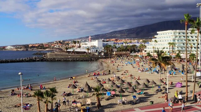 Tenerife South, Adeje Spain - sand beach with palms interesting clouds and people