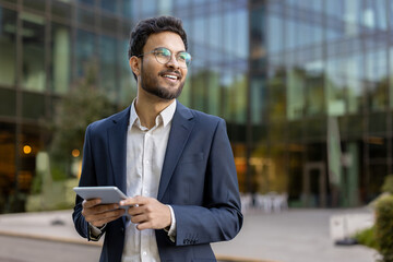Confident business man using tablet near modern office building