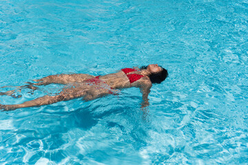 Young woman floating and relaxing in swimming pool