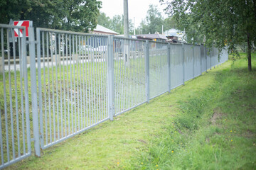 A fence along the territory. A gray fence enclosing the stadium. Fencing on the street.