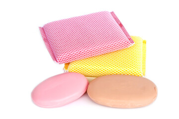 Colorful bath sponges with mesh texture and two oval soap bars placed on white background. Concept of body care, hygiene, spa, bathroom accessories, cleaning products, and healthy lifestyle.