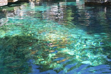 Clear, shallow water reflecting sunlight and rocks