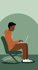 Focused young man working or studying on a laptop from a comfortable chair. Modern digital lifestyle, remote work, or online learning concept.