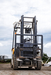 Forklift on a work site against a cloudy sky.