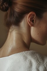 Close-up of a woman's neck and shoulders with dewy skin in soft lighting