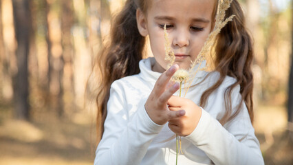 Child girl walking alone in forest park at sunshine