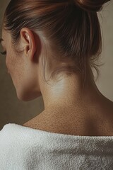 Close-up of a woman's neck and shoulders with dewy skin in soft lighting